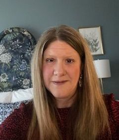 A woman is taking a selfie in front of a bed in a bedroom.