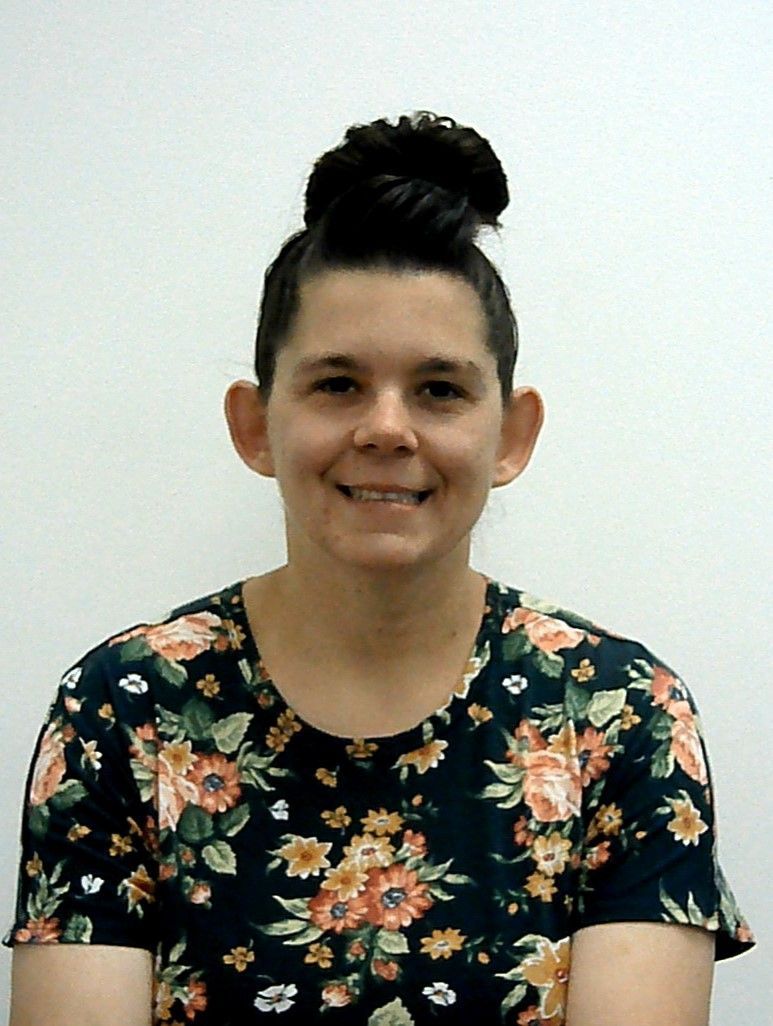 A woman wearing a floral shirt is smiling for the camera