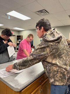 A group of men are standing around a counter in a room.