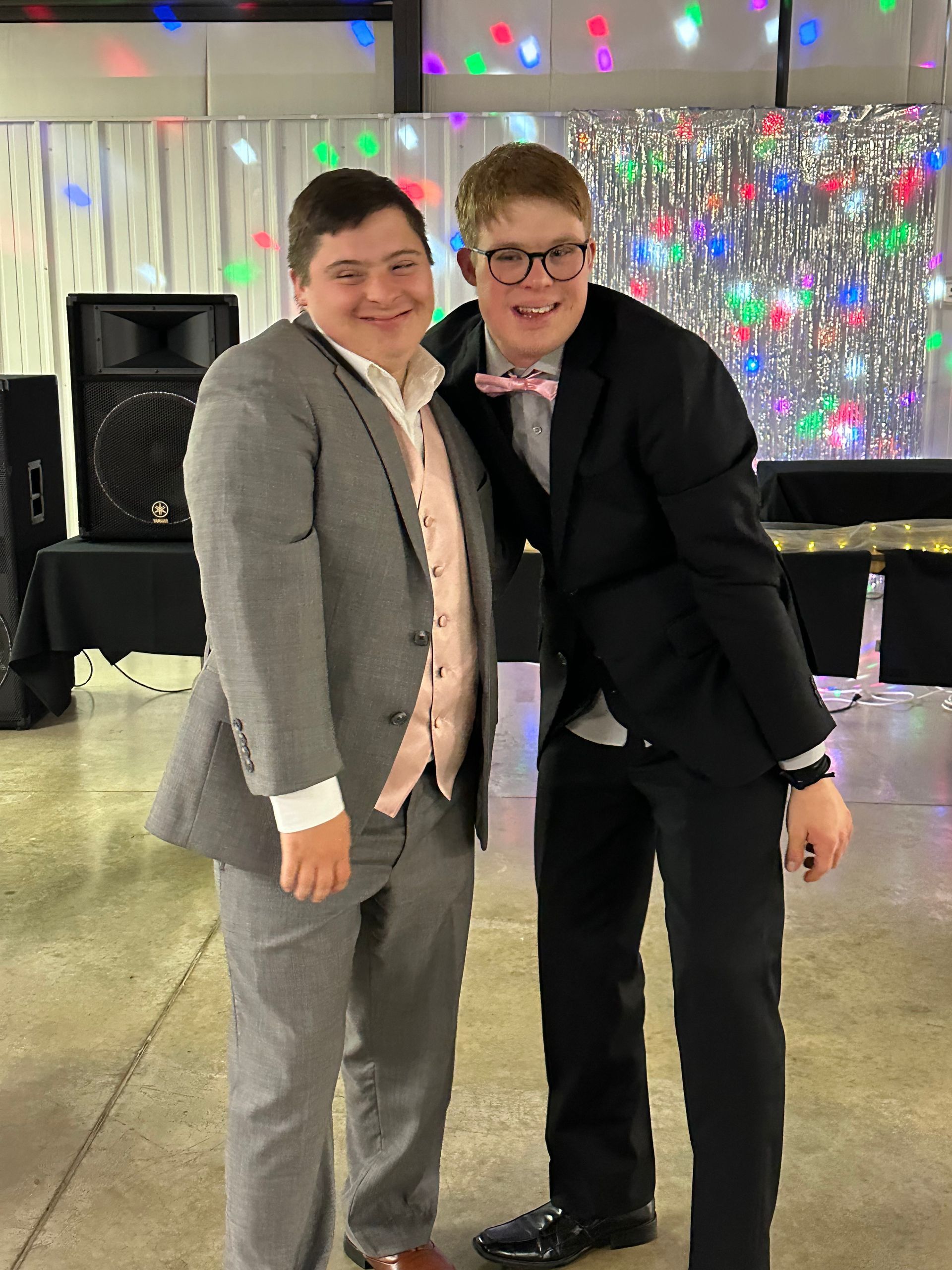 Two young men in suits and bow ties are posing for a picture.