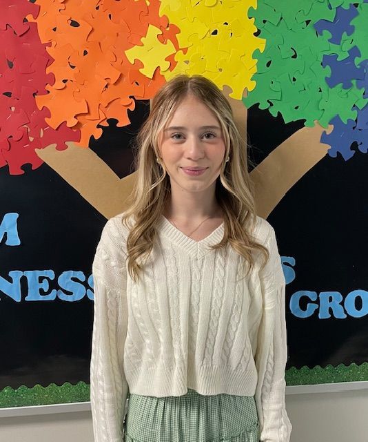 A woman wearing a floral shirt is smiling for the camera