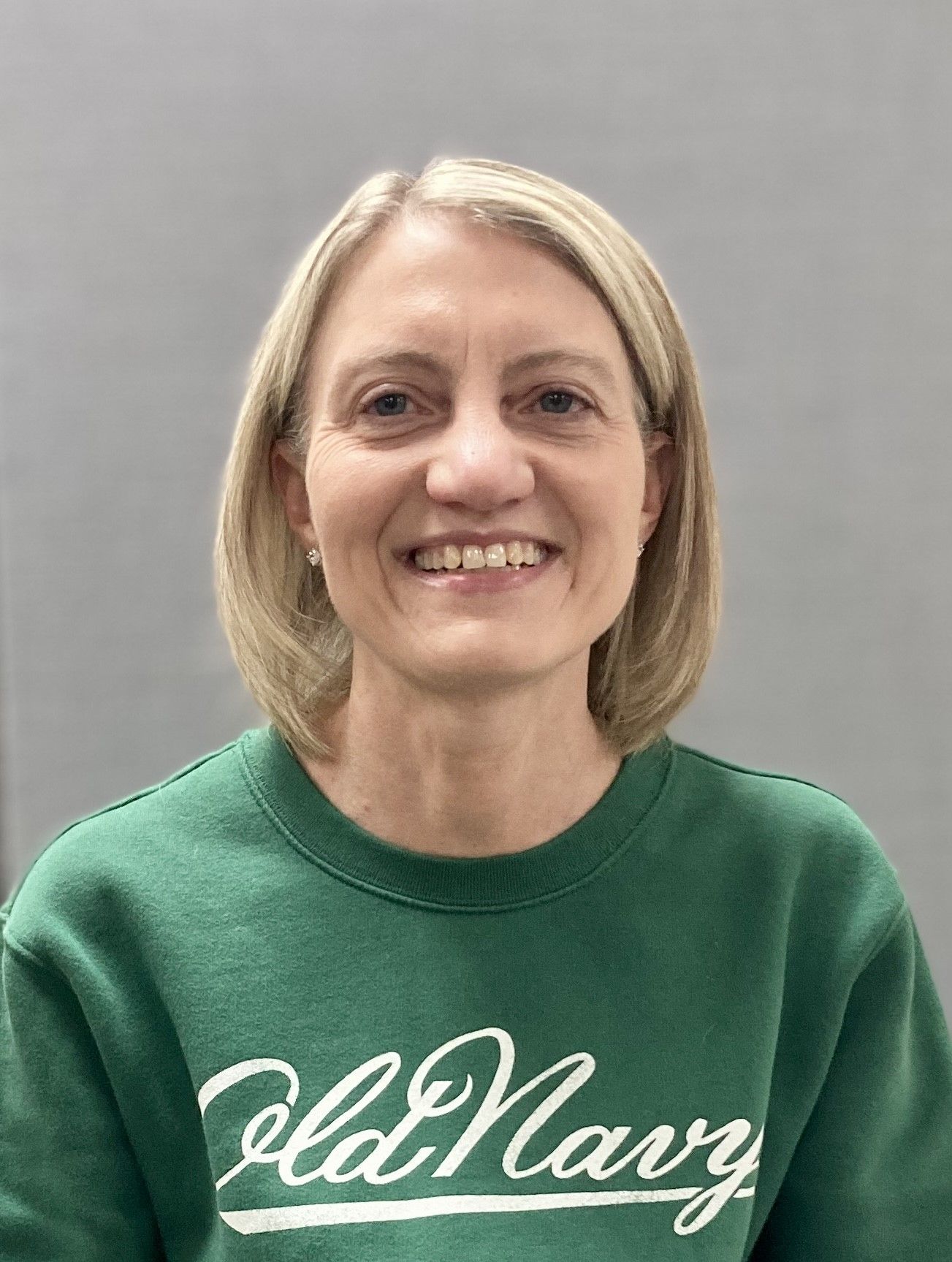 A woman is wearing a green old navy sweatshirt and smiling.