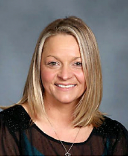 A woman wearing a black shirt and a necklace is smiling for the camera.