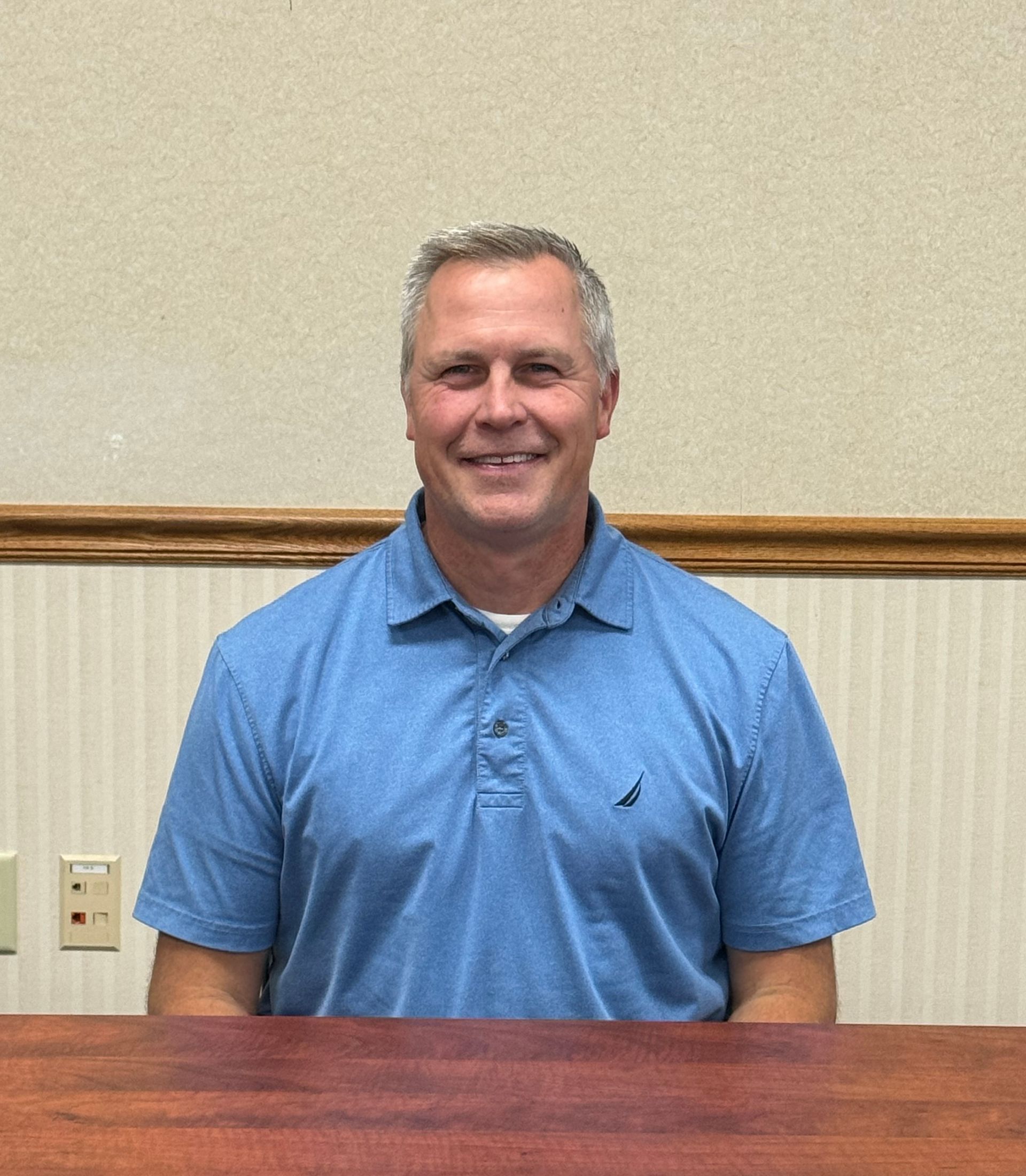 A man in a blue shirt is sitting at a table. This is Matt Dwenger.