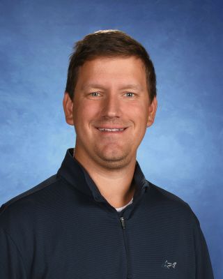 A man in a blue jacket is smiling for the camera.