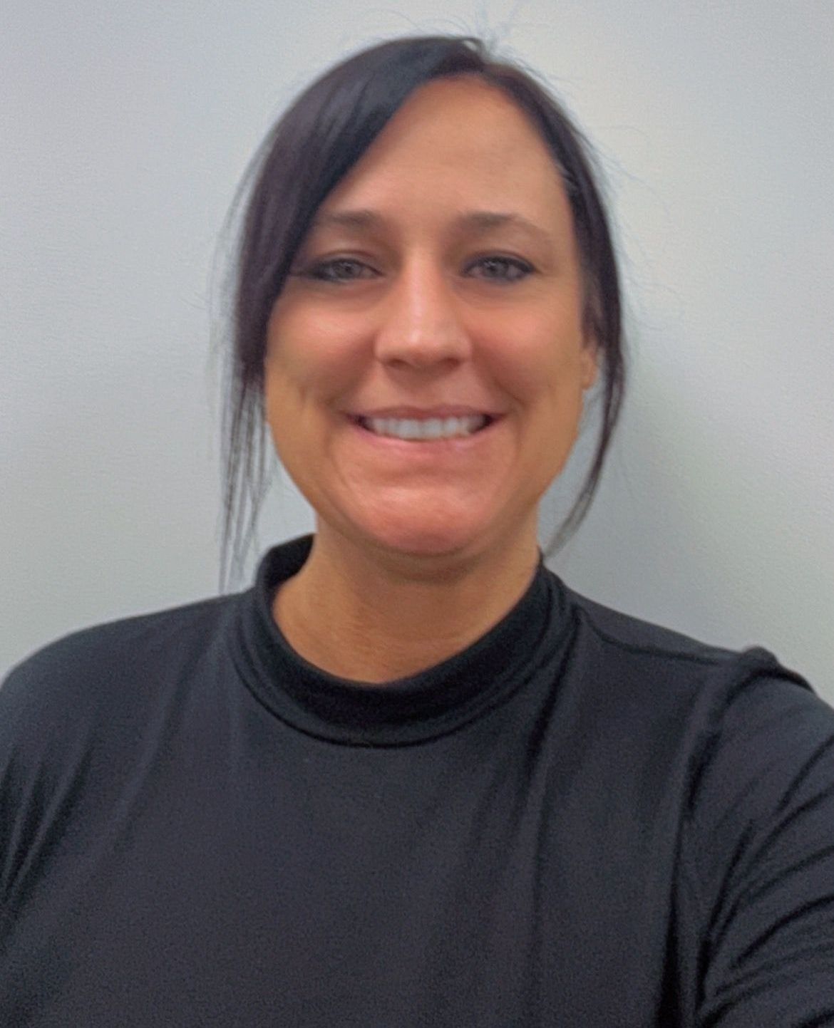 A woman in a black shirt is smiling for the camera.
