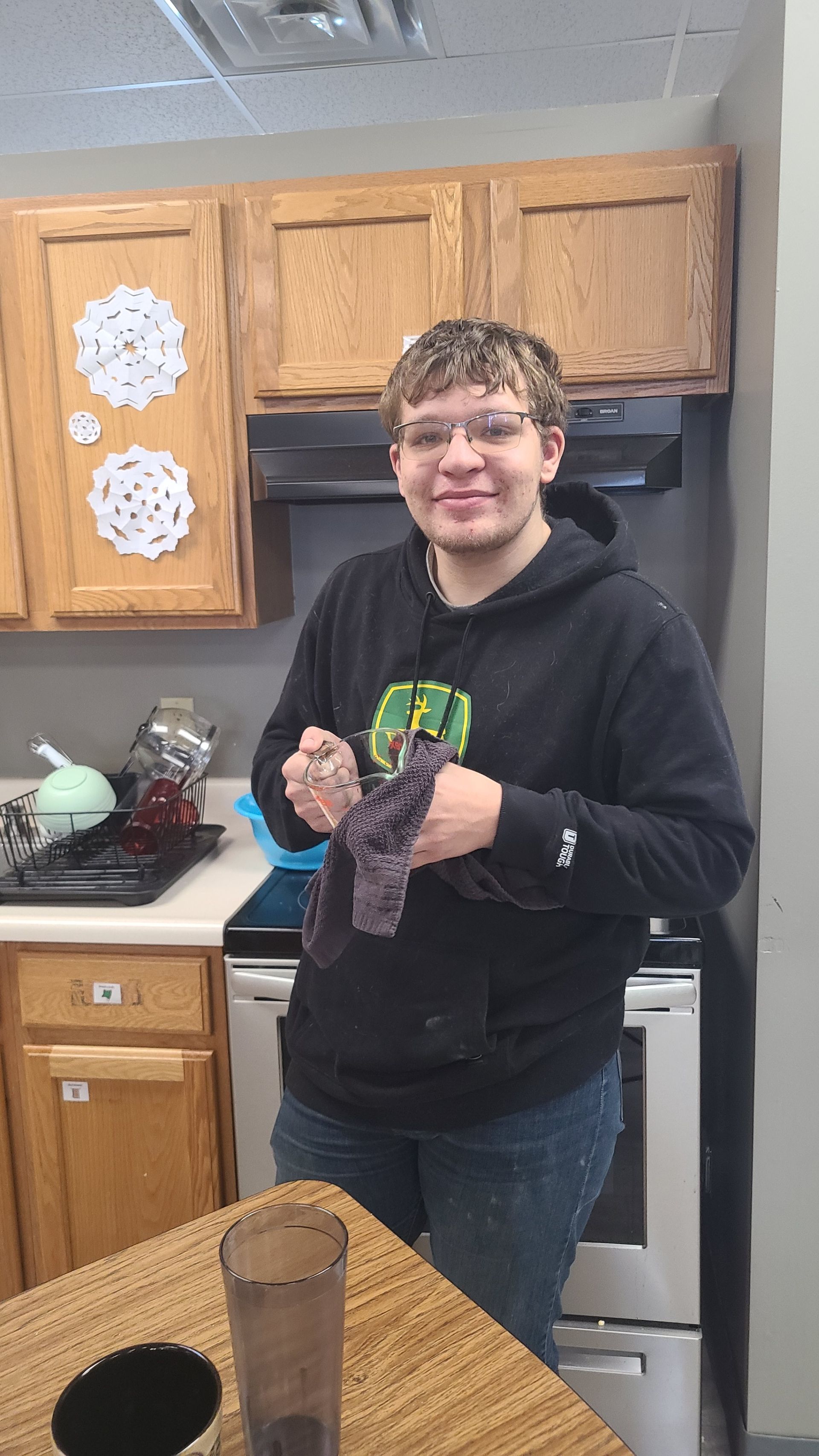 A woman in a striped shirt is standing next to a man in a wheelchair.