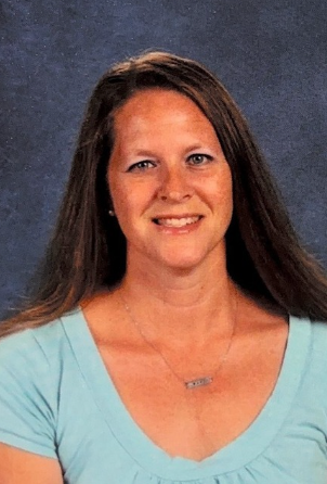 A woman wearing a blue shirt and a necklace is smiling for the camera. This is Stacey Van Fleet.