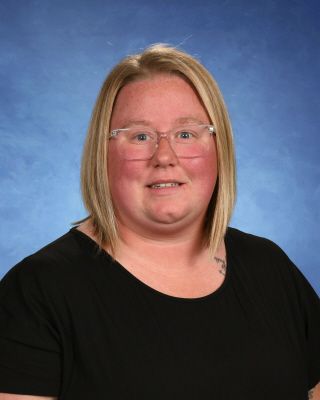 A woman with red hair is wearing a green sweater and smiling.