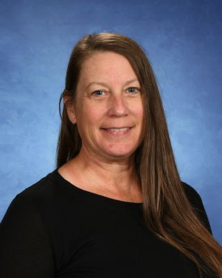 A woman with long hair is wearing a black shirt and smiling for the camera.