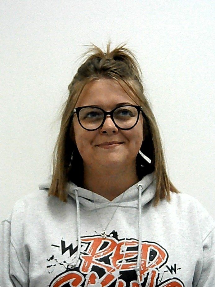 A woman wearing glasses and a hoodie is smiling for the camera.