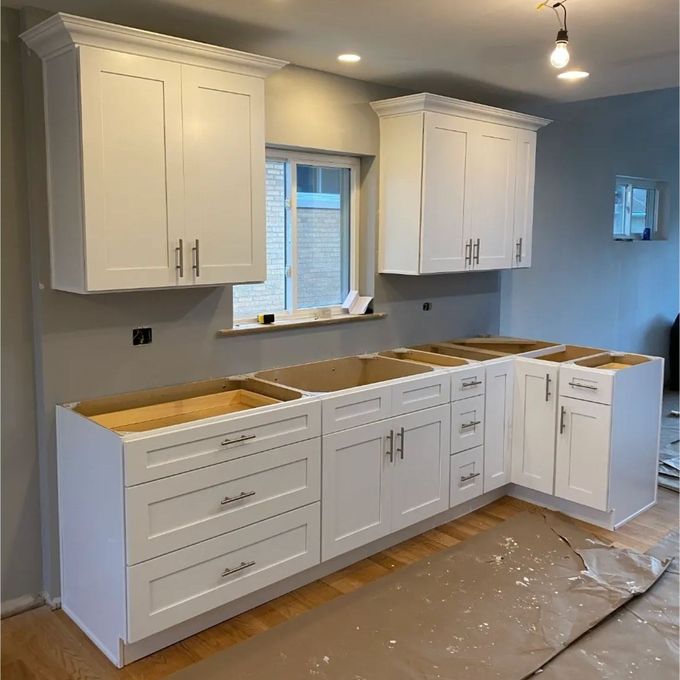 A kitchen under construction with white cabinets and drawers