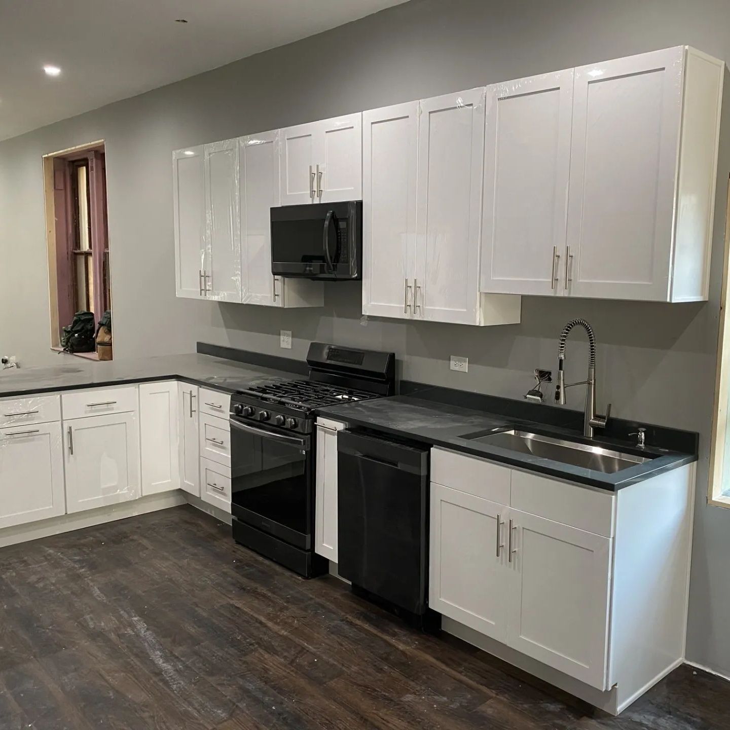 A kitchen with white cabinets, stainless steel appliances, granite counter tops, and a stove.