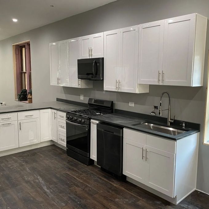 A kitchen with white cabinets , black appliances , and a sink.