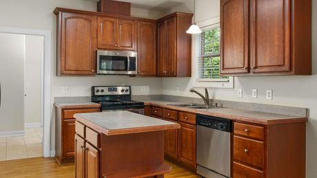 A kitchen with wooden cabinets, stainless steel appliances, and a large island.