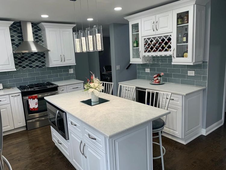 A kitchen with white cabinets , stainless steel appliances , and a large island.