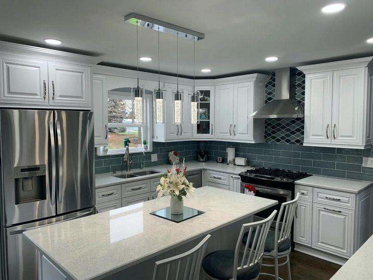 A kitchen with white cabinets , stainless steel appliances , and a large island.