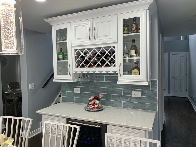 A kitchen with white cabinets and a wine rack above the counter.