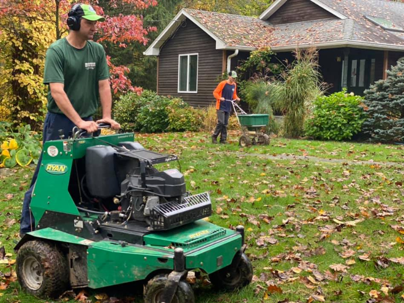 A man is riding a lawn mower in front of a house.