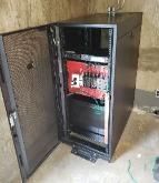 A server rack with the door open in a room.