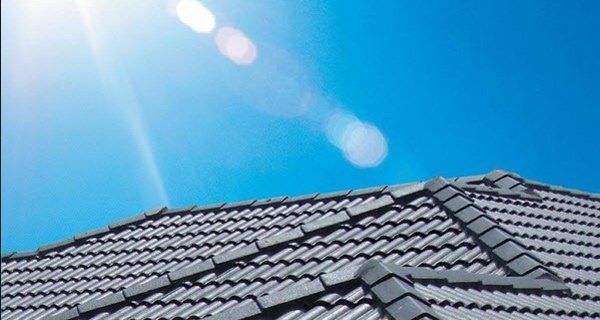 Gray tiled roof under a bright blue sky with sun glare.