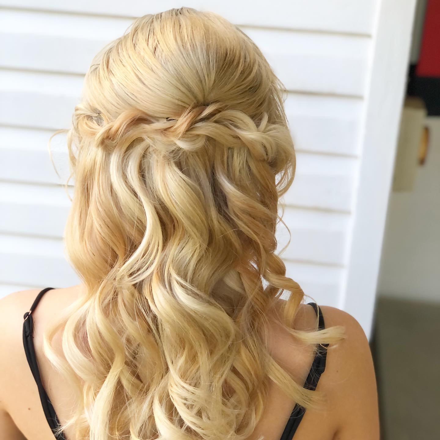 A woman with blonde hair is wearing a braided half up half down hairstyle.