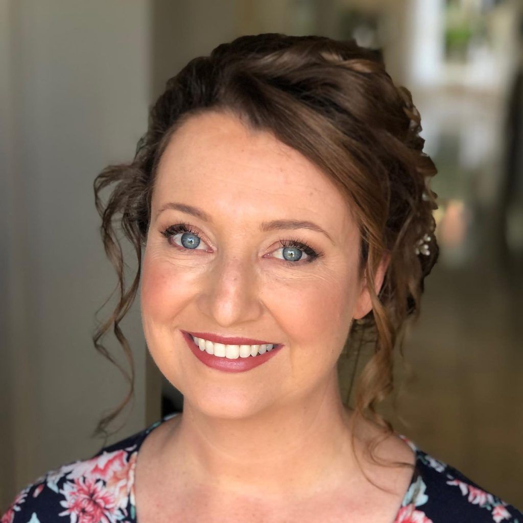 A woman in a floral shirt is smiling for the camera.