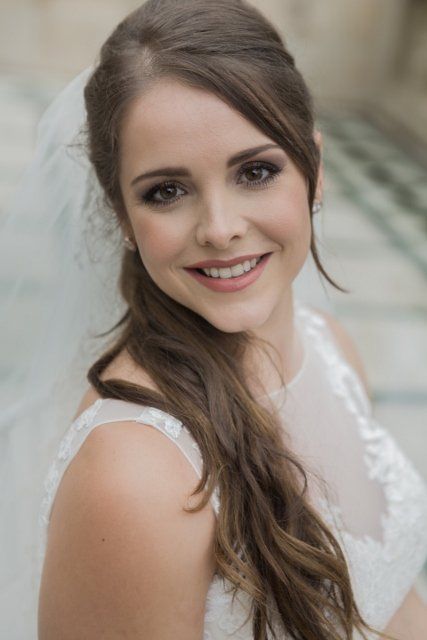 The bride is wearing a veil and smiling for the camera.