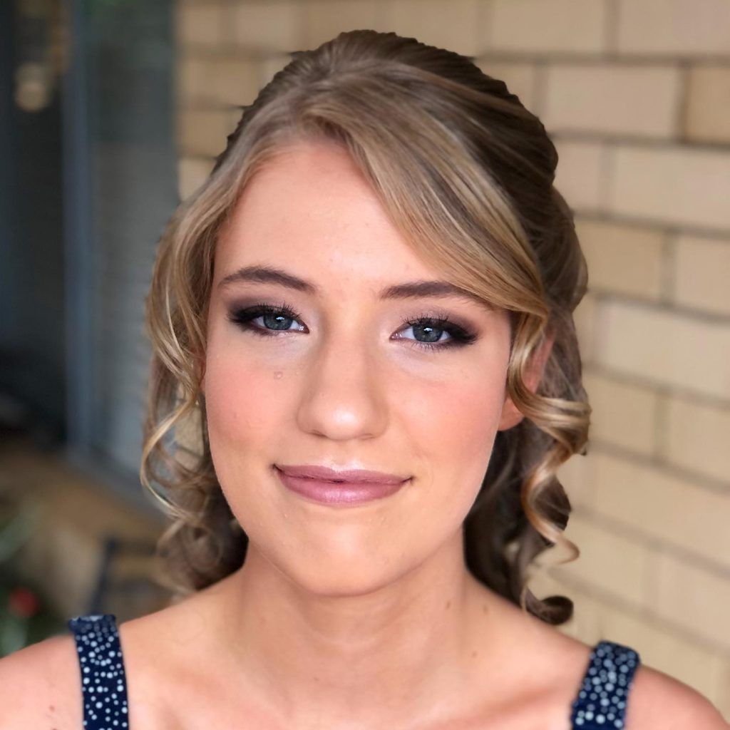 A close up of a woman 's face with a brick wall in the background
