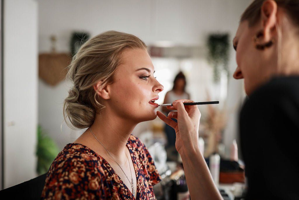 A woman is getting her makeup done by a makeup artist.