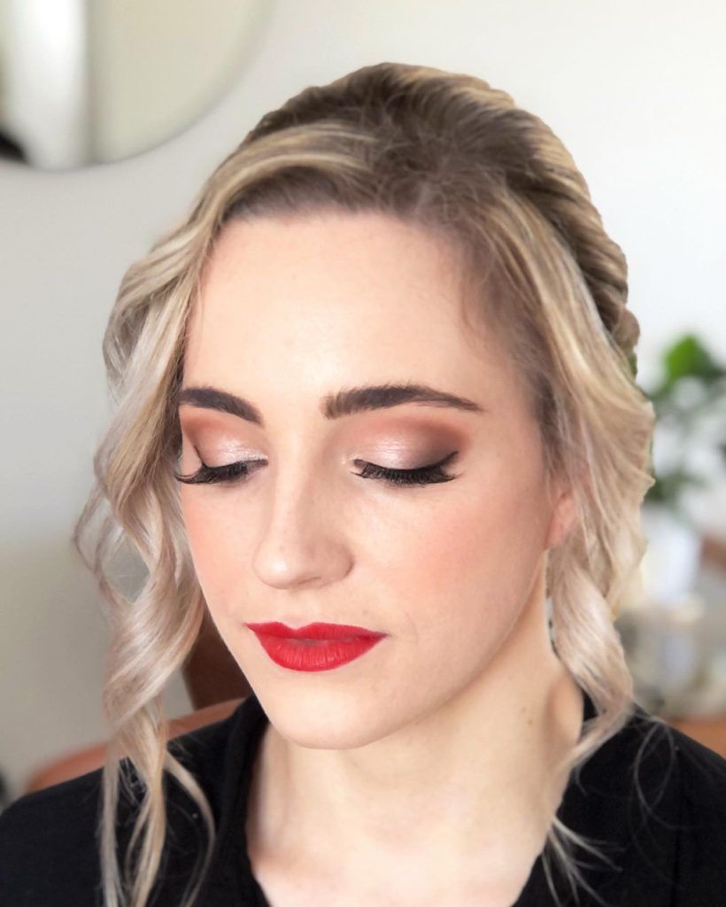 A woman with blonde hair and red lipstick is wearing a black shirt.