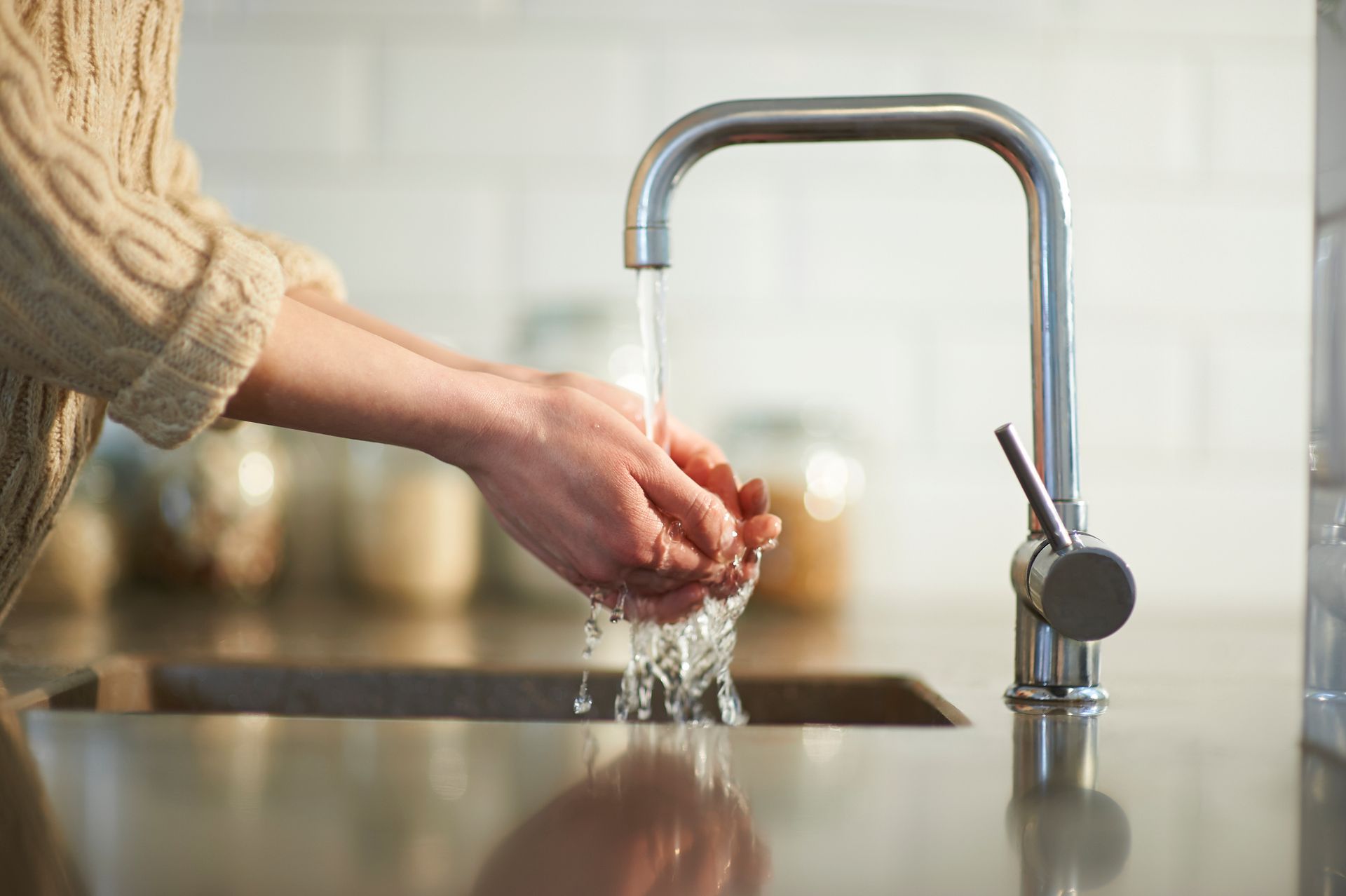 A person is washing their hands in a kitchen sink.