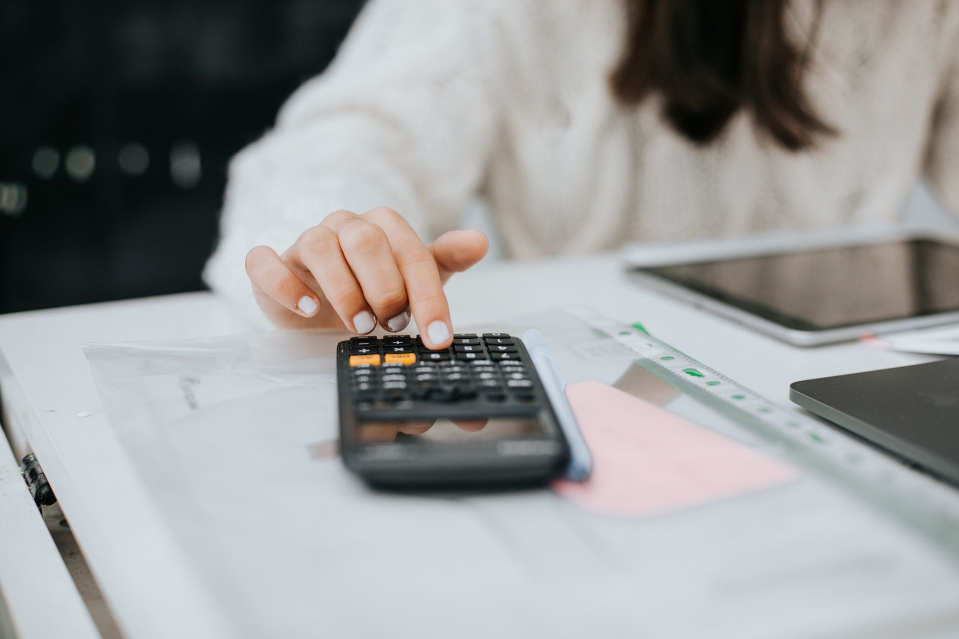 A woman is sitting at a table using a calculator.