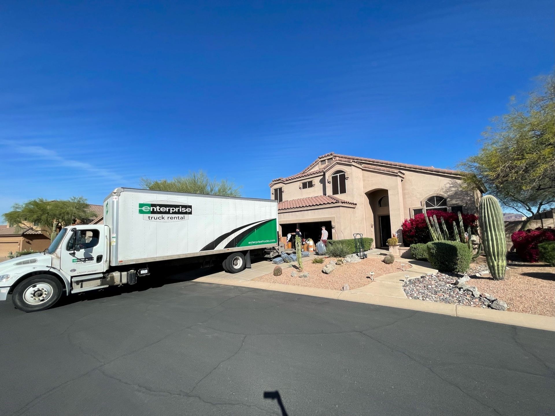 A moving truck is parked in front of a large house.