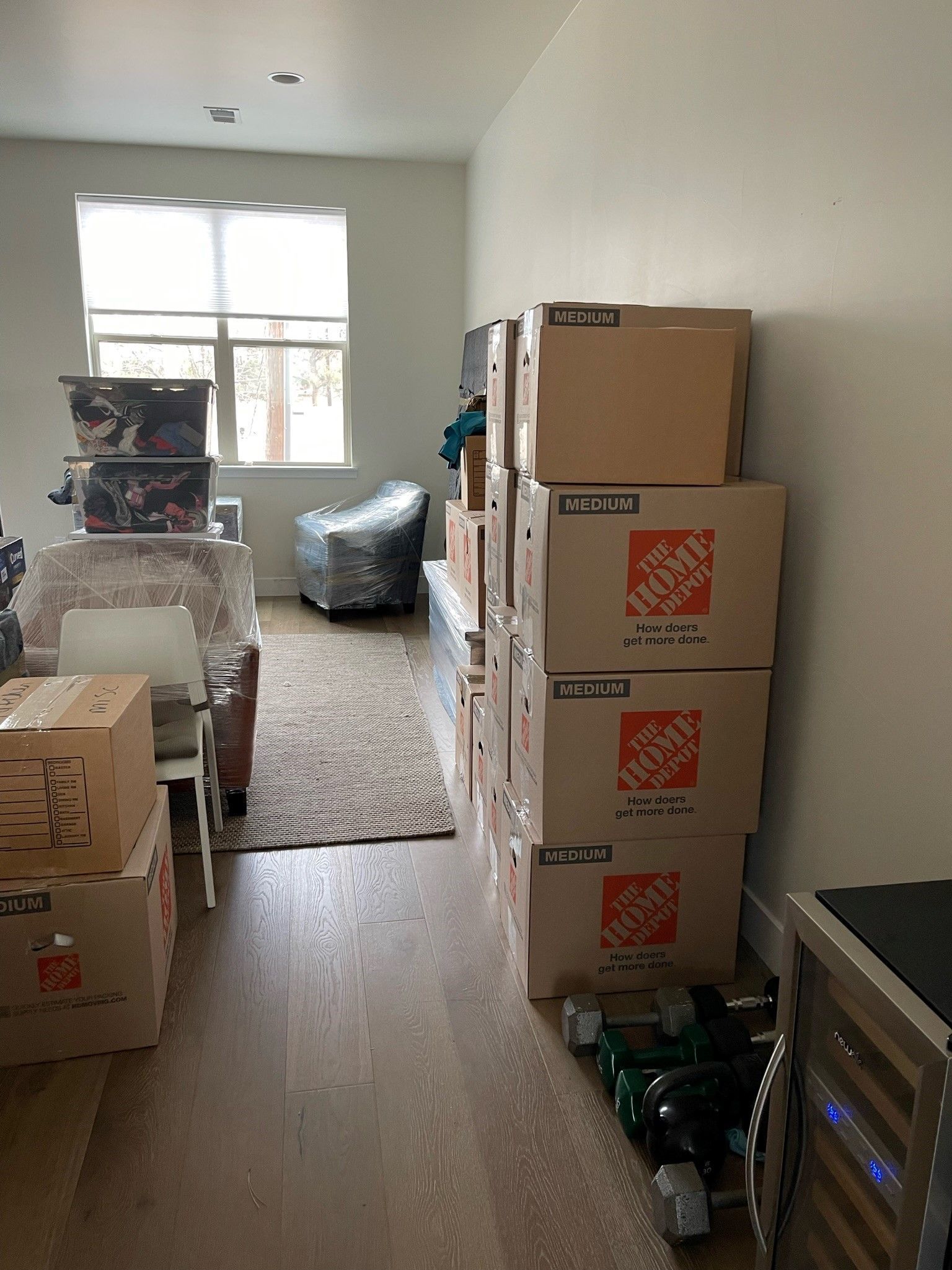 A living room filled with boxes and a refrigerator.