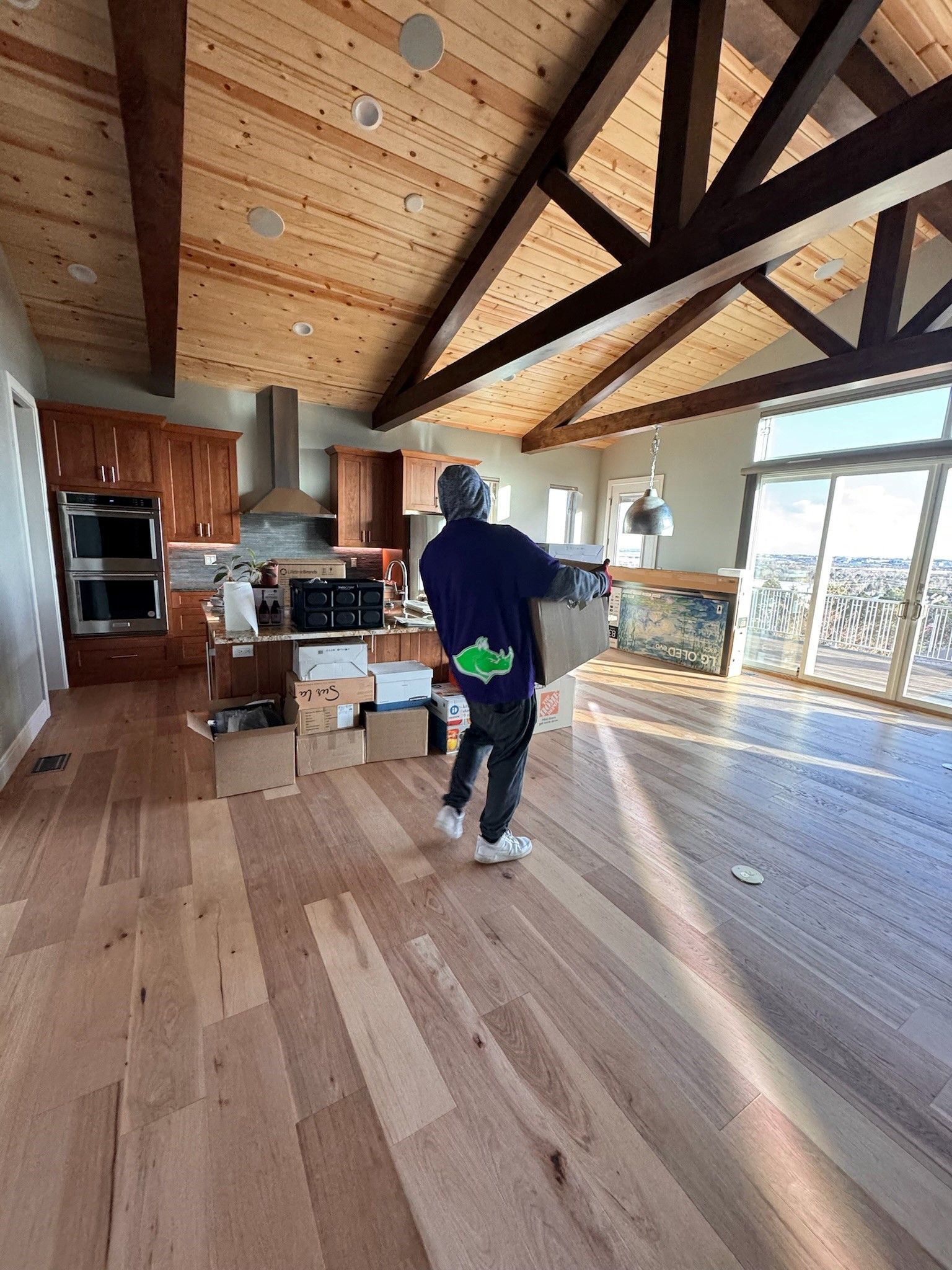 A man is standing in an empty kitchen with wooden floors.