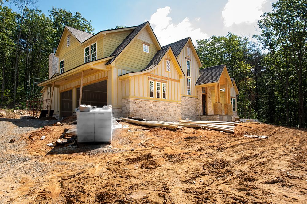 A large house is being built in the middle of a dirt field.