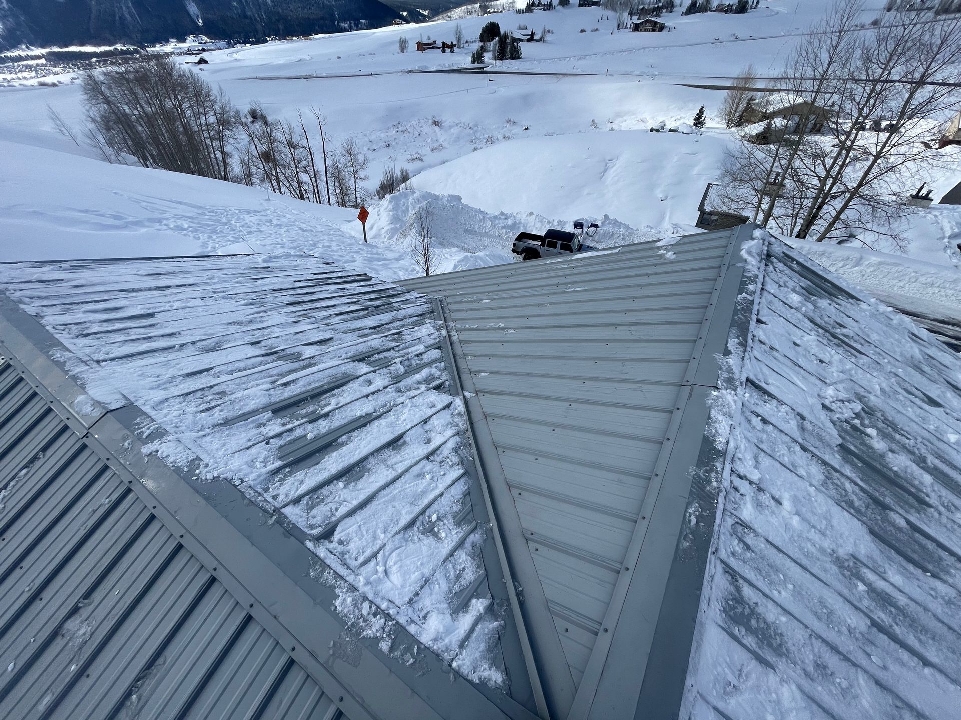 Snow-covered metal roof in a snowy mountain landscape.