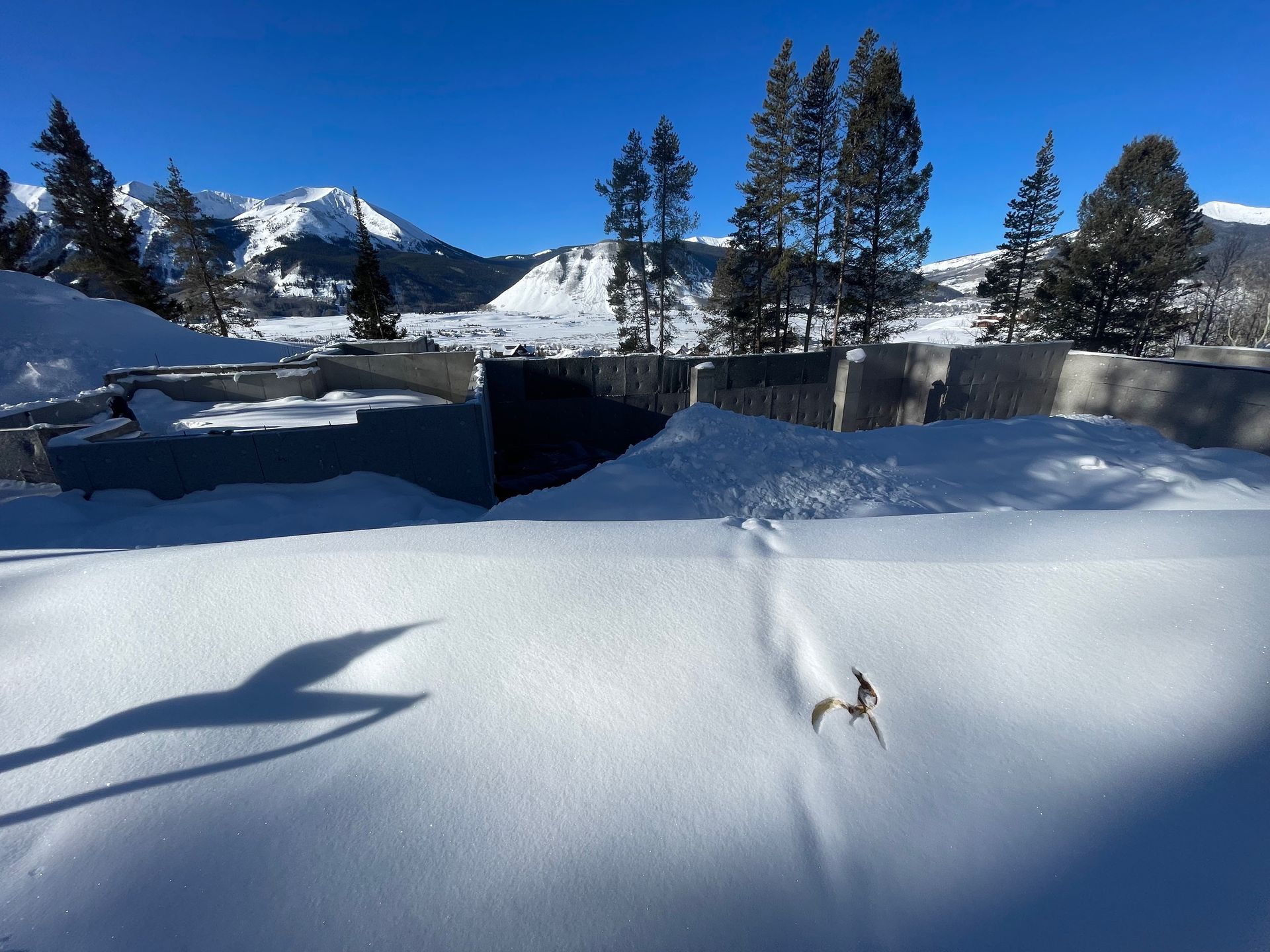 Snowy landscape with mountains in the background, shadowed foreground, bright sunny day.