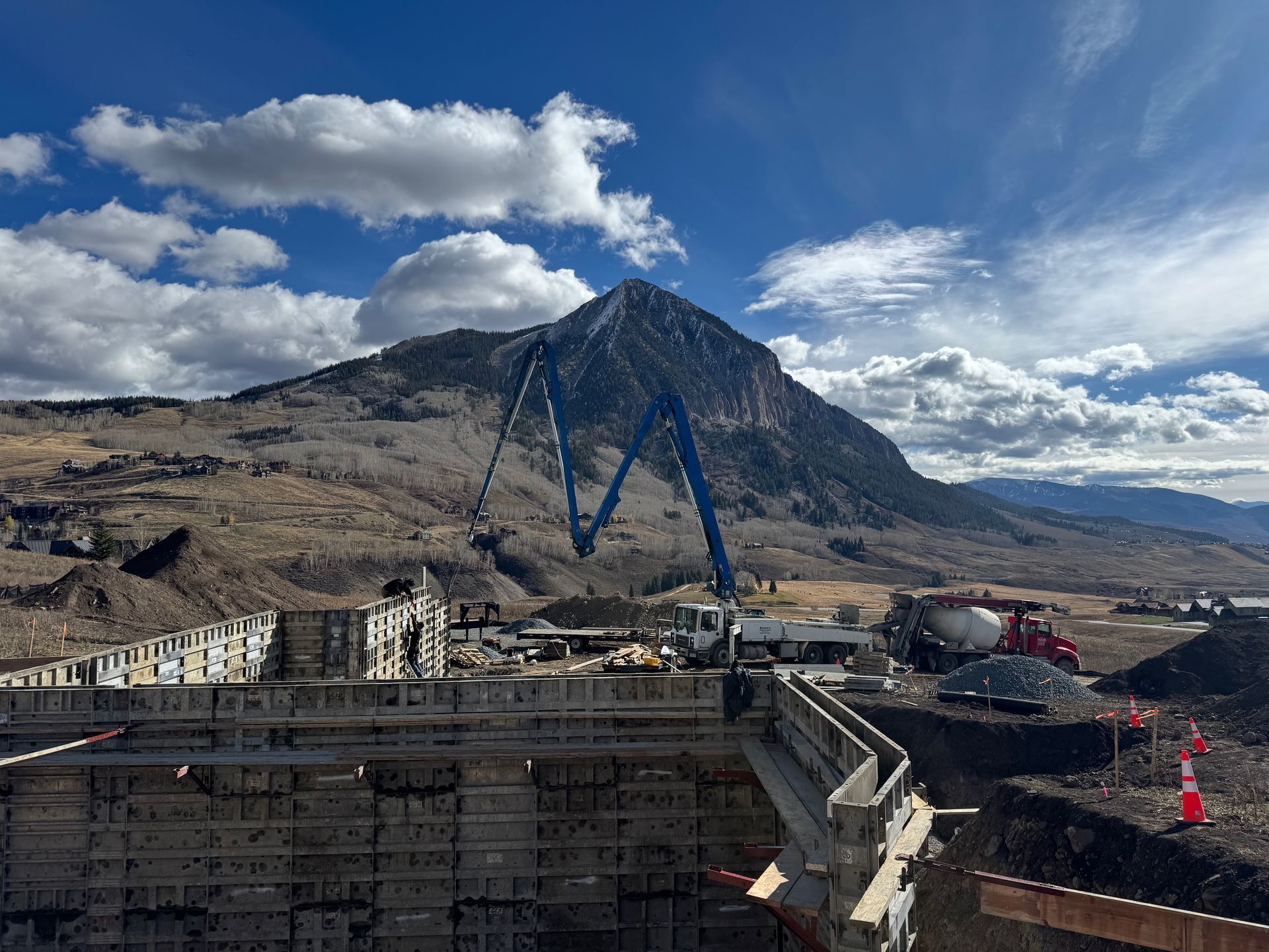 Construction site with a concrete pump extended toward a mountain.