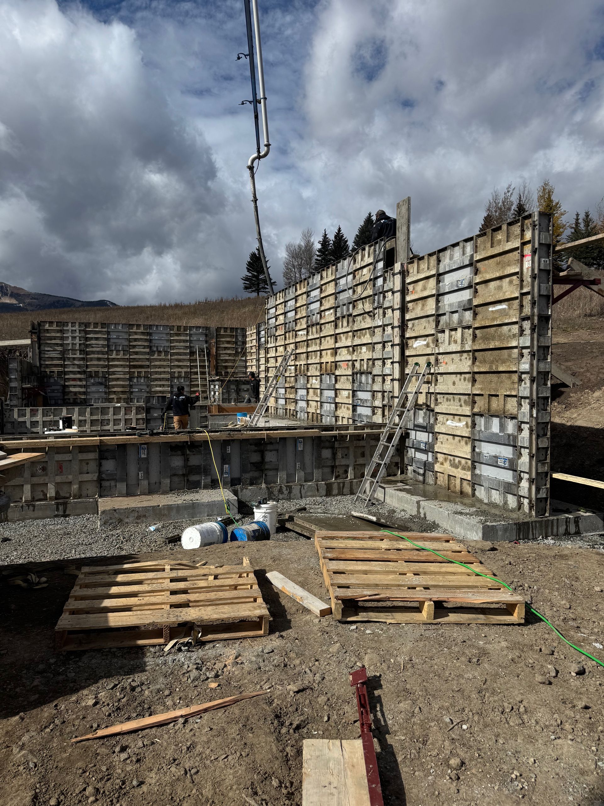 Concrete being poured into forms at a construction site, with pallets in foreground.