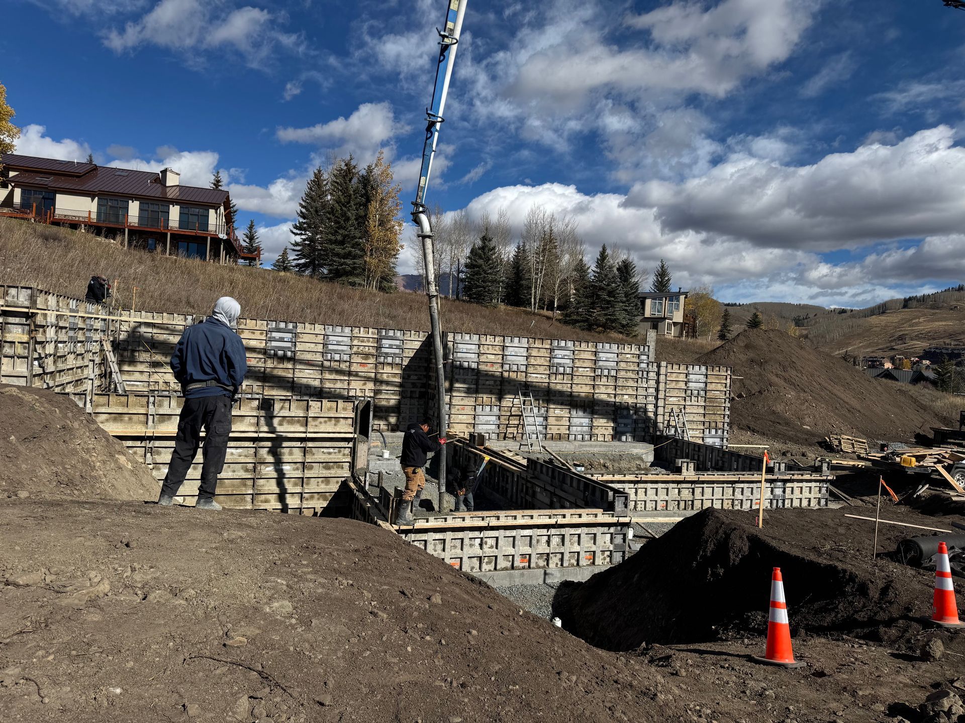 Construction site with concrete forms; a worker observes concrete pouring 