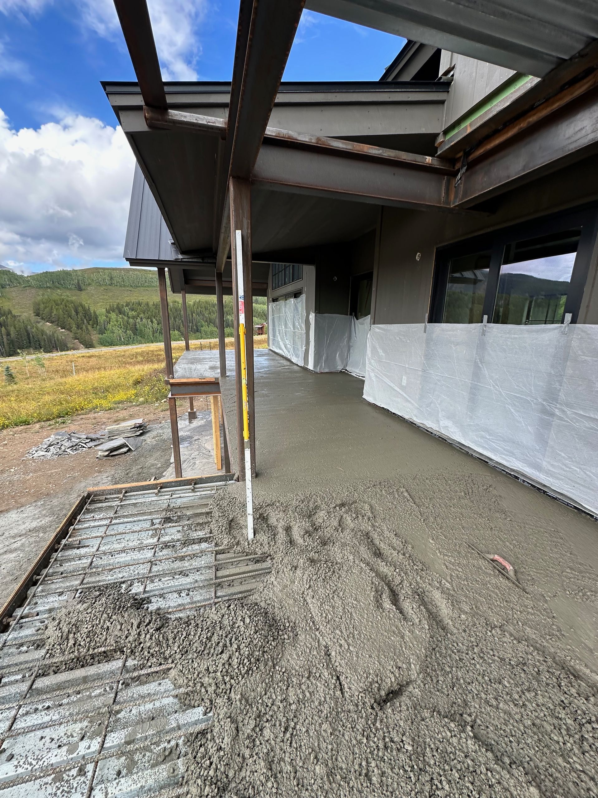 Concrete patio under construction with metal supports next to a building.
