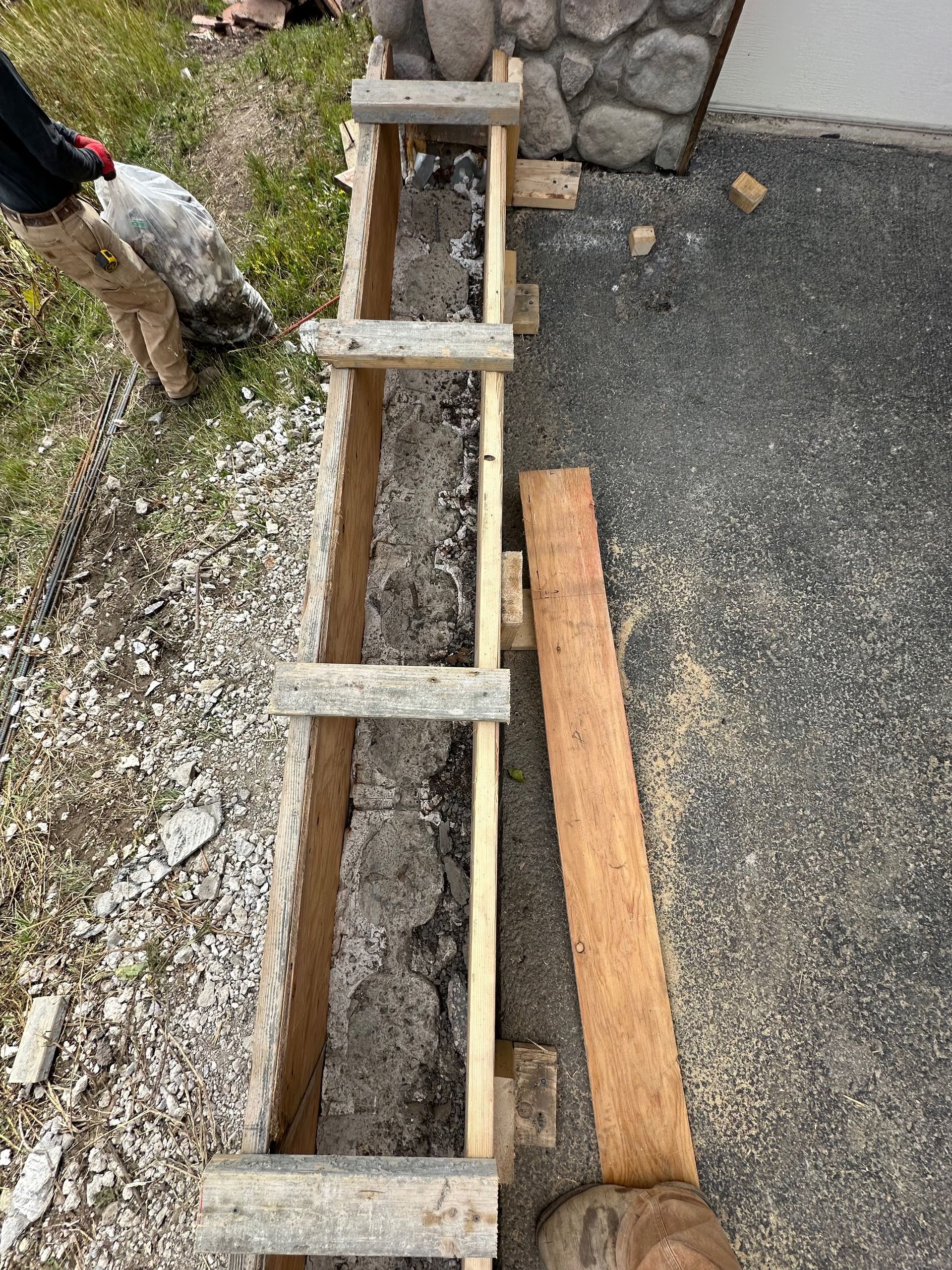 Formwork for a concrete structure with wooden bracing. A person stands nearby.