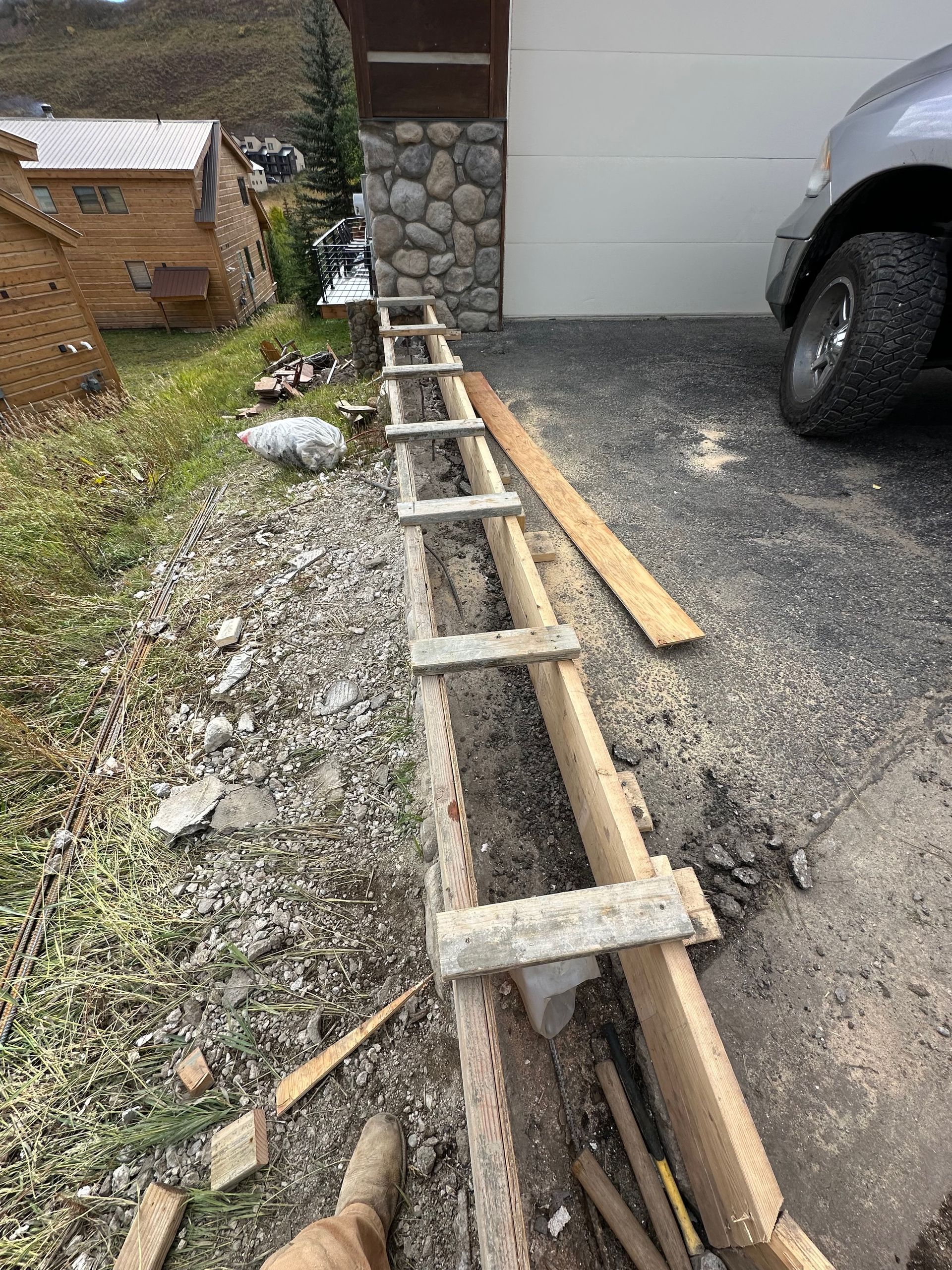Wooden formwork for a retaining wall next to a driveway and building.