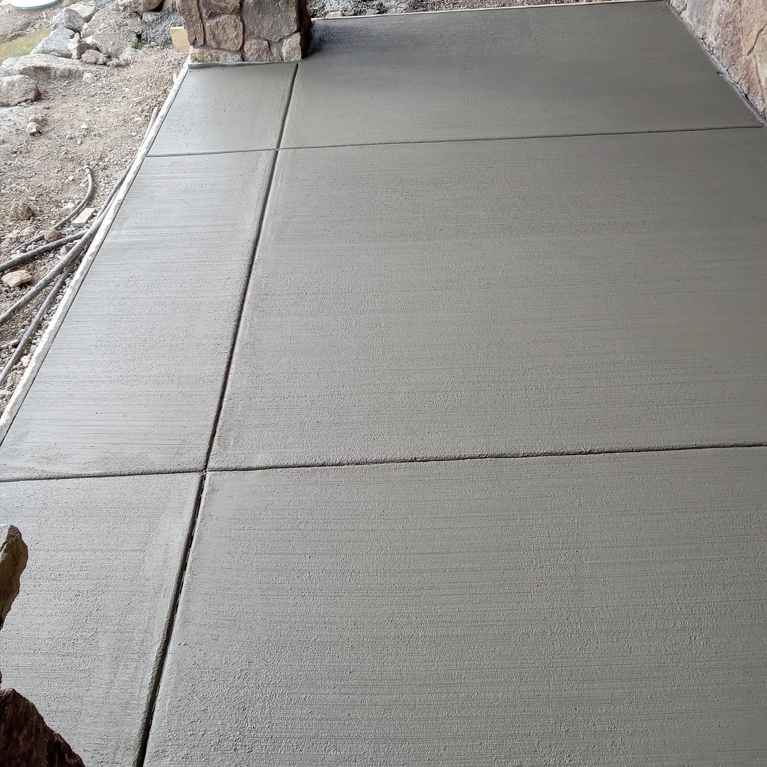 Newly poured gray concrete patio with control joints.