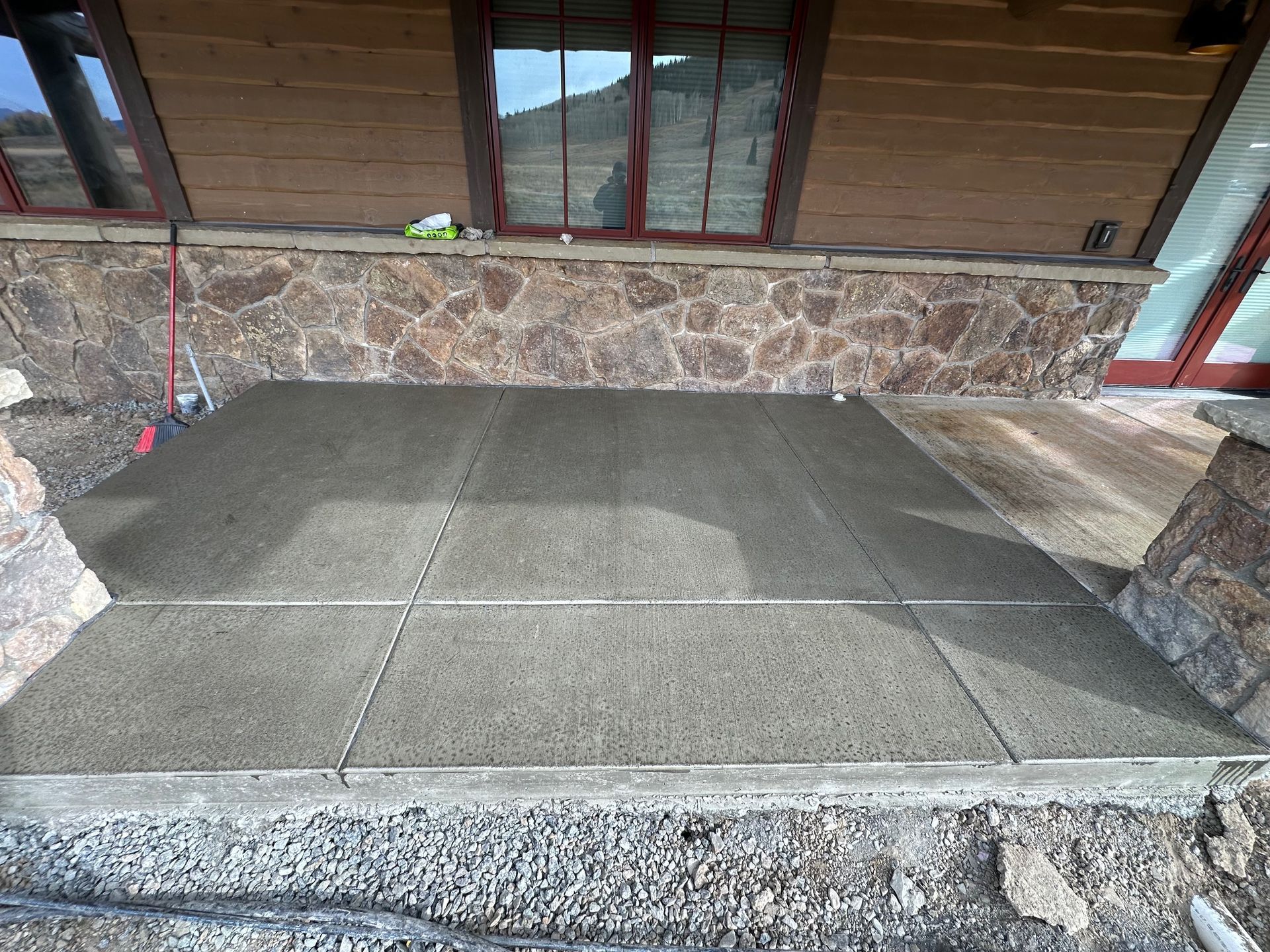 Concrete patio with textured surface, divided into square sections, set in a stone-walled outdoor area.