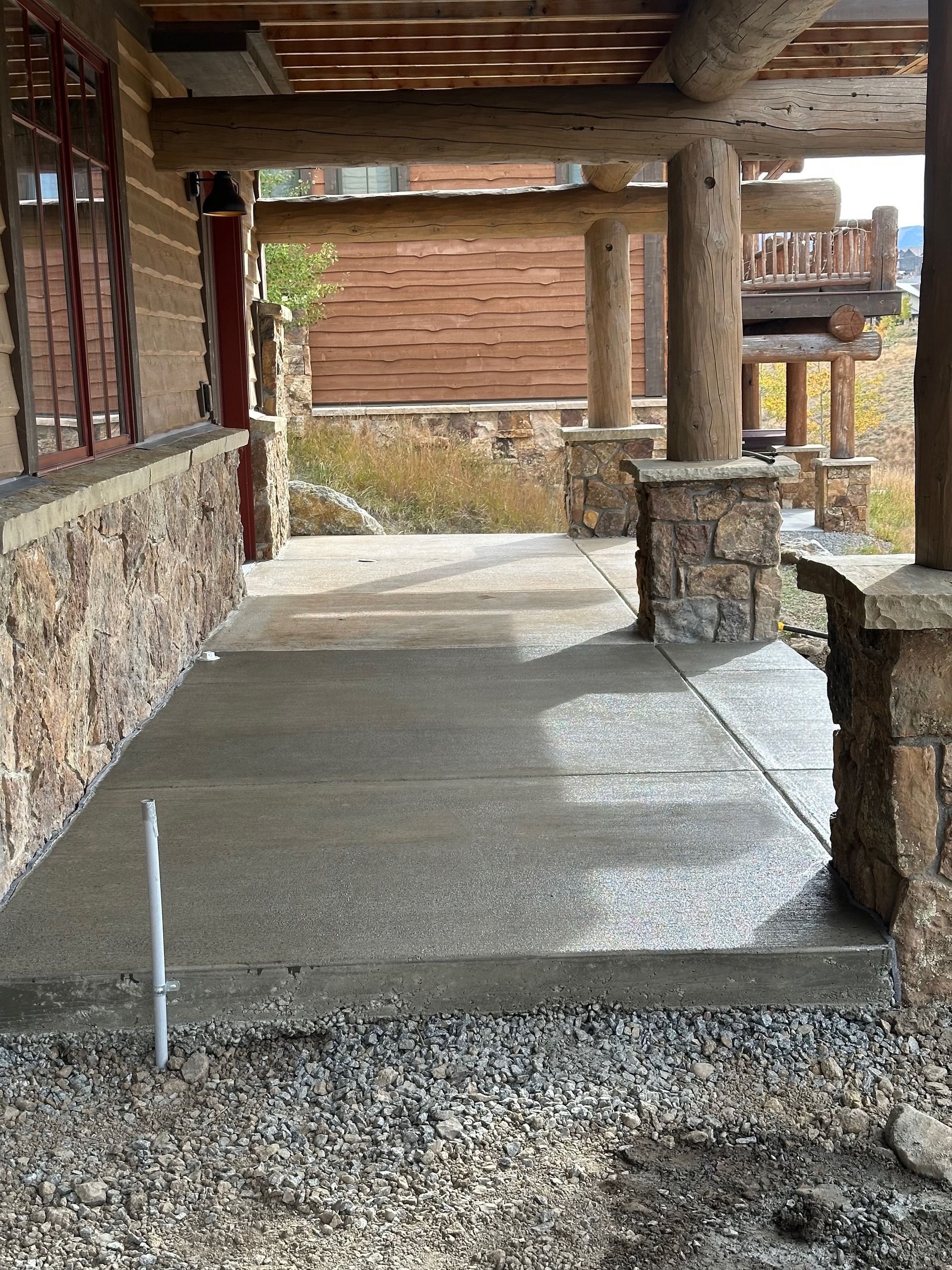 Covered porch with stone columns and concrete floor.