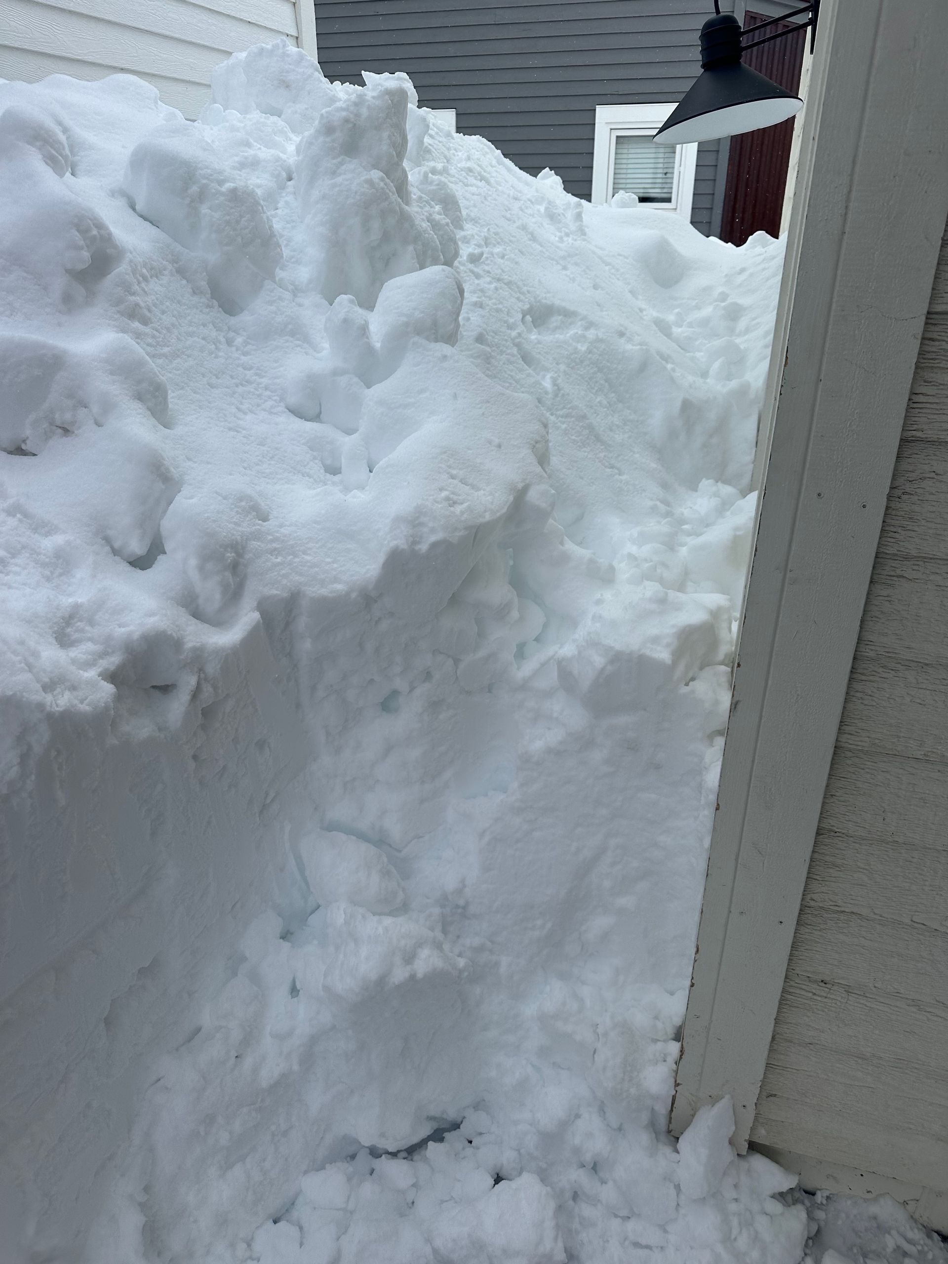 Large pile of snow next to a white building.