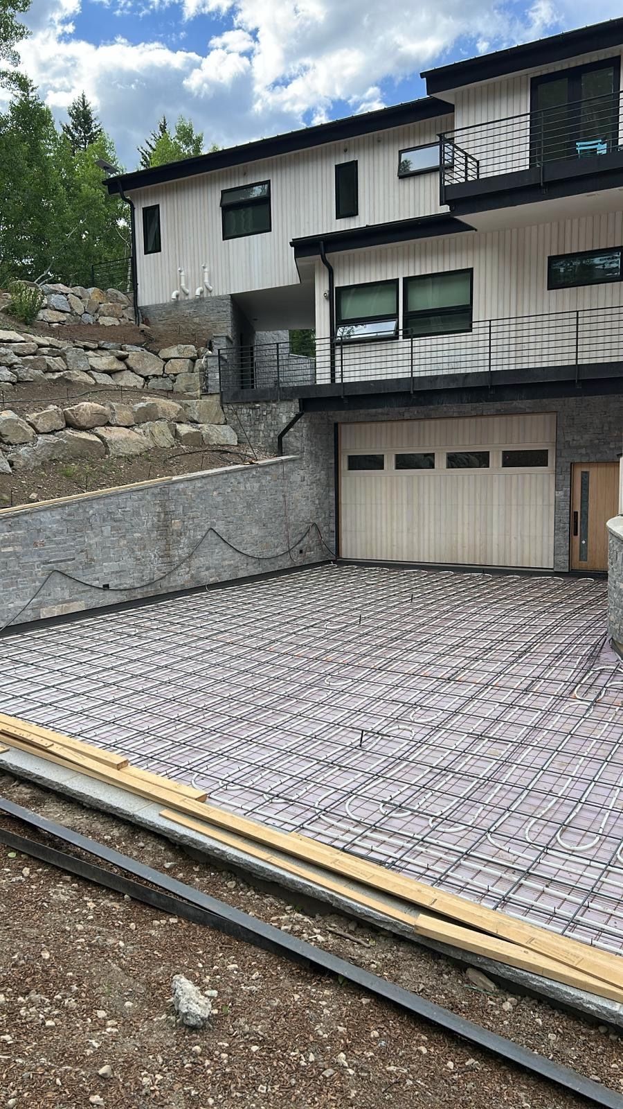 Construction site: concrete rebar driveway in front of a modern two-story home with light-colored siding